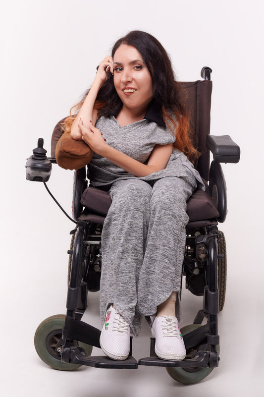 Woman in wheelchair smiling and happy to be wearing adaptive elastic clothing
