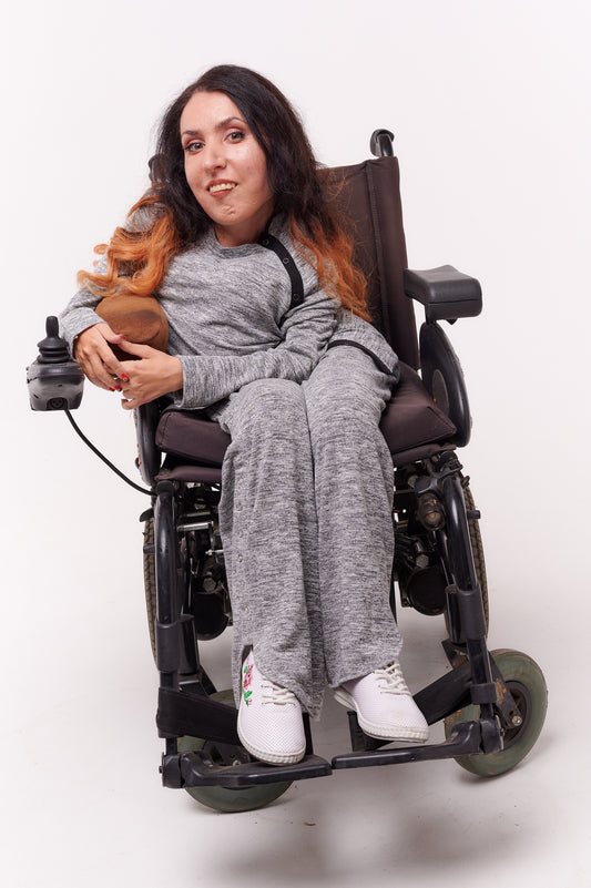 Woman in wheelchair wearing adaptive clothing, showcasing inclusivity and accessibility in fashion